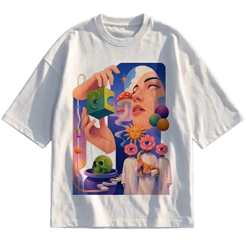 A white short-sleeve crewneck t-shirt featuring a large, colorful surreal graphic print on the front. The illustration depicts a woman's face, a hand holding a green puzzle piece, a skull, and abstract cosmic elements in shades of blue, pink, purple, and green.